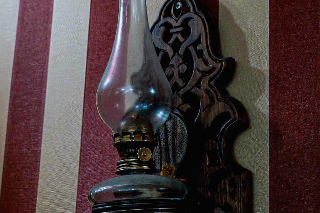 Oymalı ahşap raf üzerinde eski gaz lambası.